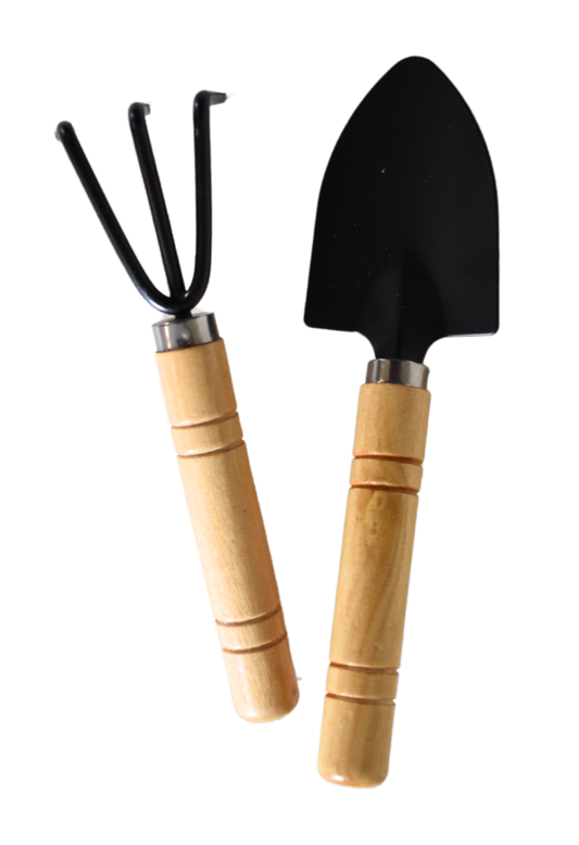 Ein kleines Gartenwerkzeug-Set bestehend aus einer schwarzen Handschaufel und einer kleinen dreizinkigen Harke mit Holzgriffen, nebeneinander liegend.